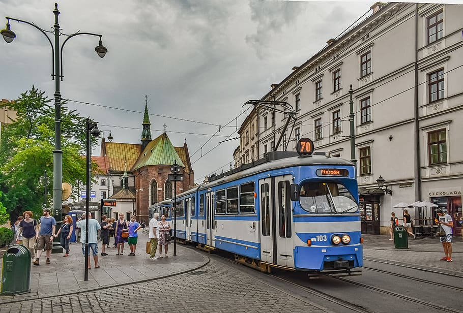 Photo of a blue tram in a street with old palaces and a church in the background