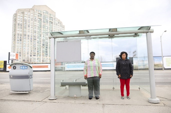 Photo of a man and a woman standing at a bus stop