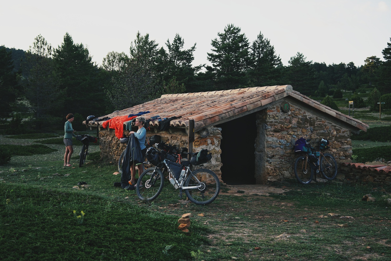 Photo of bikers standing outside a rural shelter made of stones