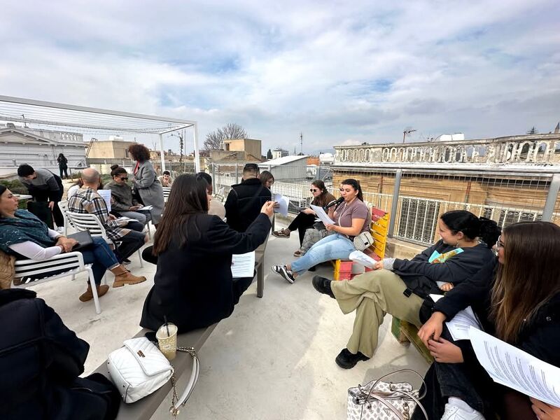 Photo of young people sitting in a circle on a rooftop