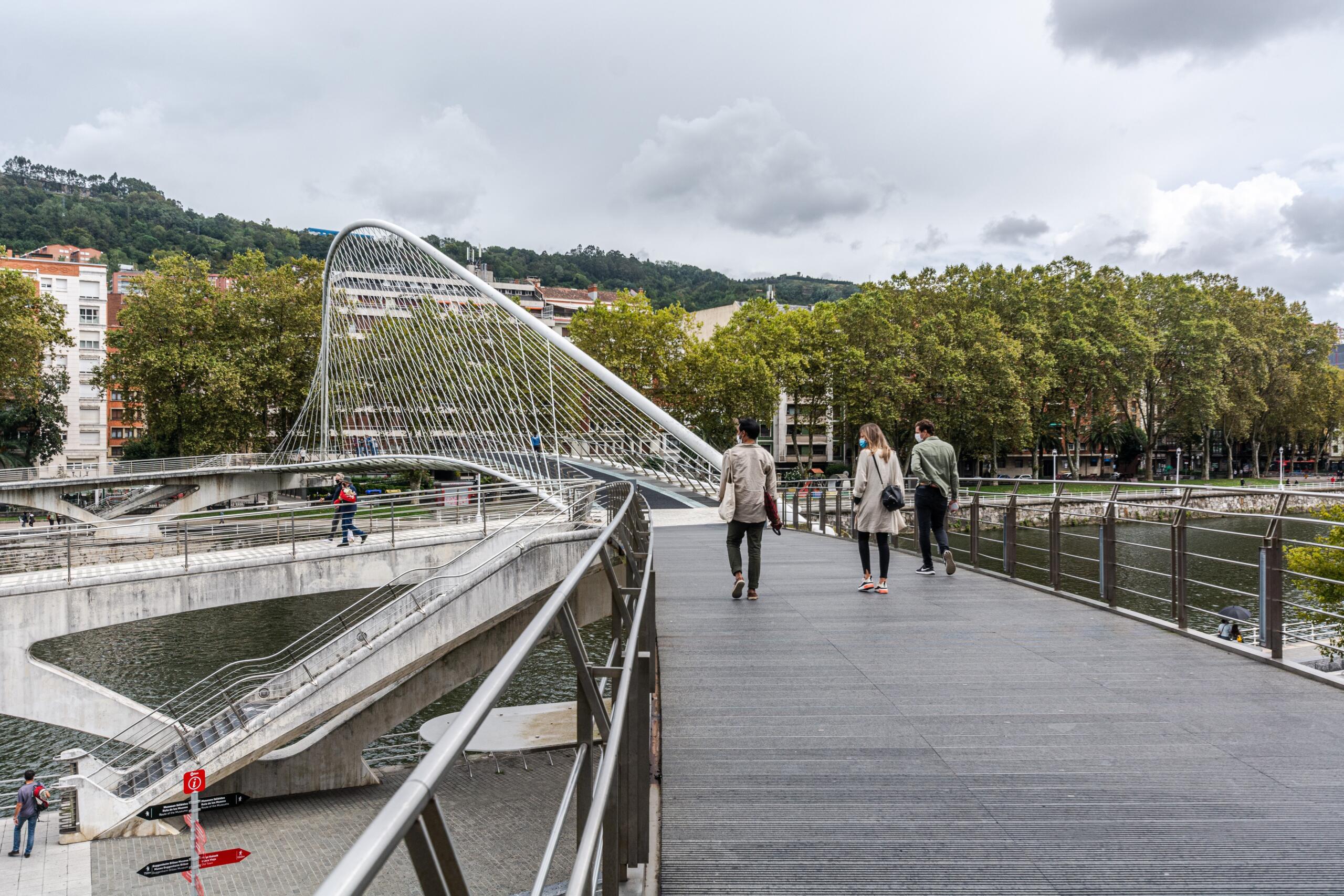 Pedestrians walking on the Zubizuri Bridge in Bilbao.