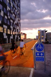 people riding bicycles inside bicycle lane beside skyscraper