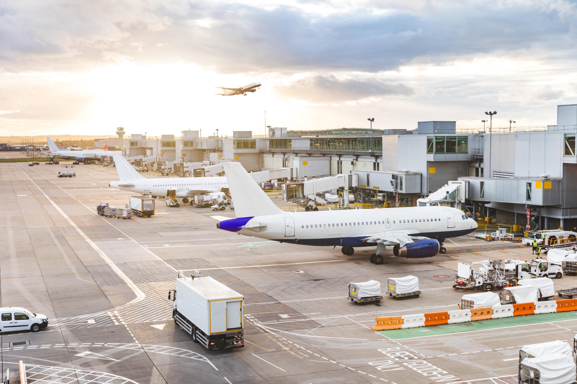 A photo of a busy airport, with multiple airplanes and the sun shining.